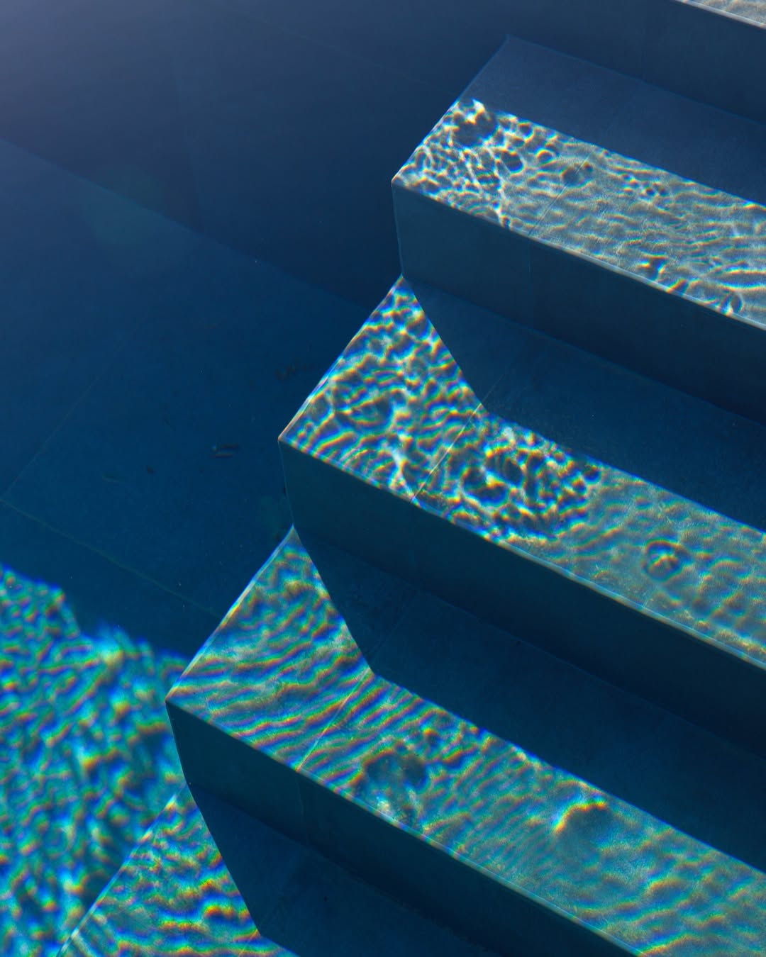 Escalier immergé d'une piscine, détail de l'eau sur la pierre