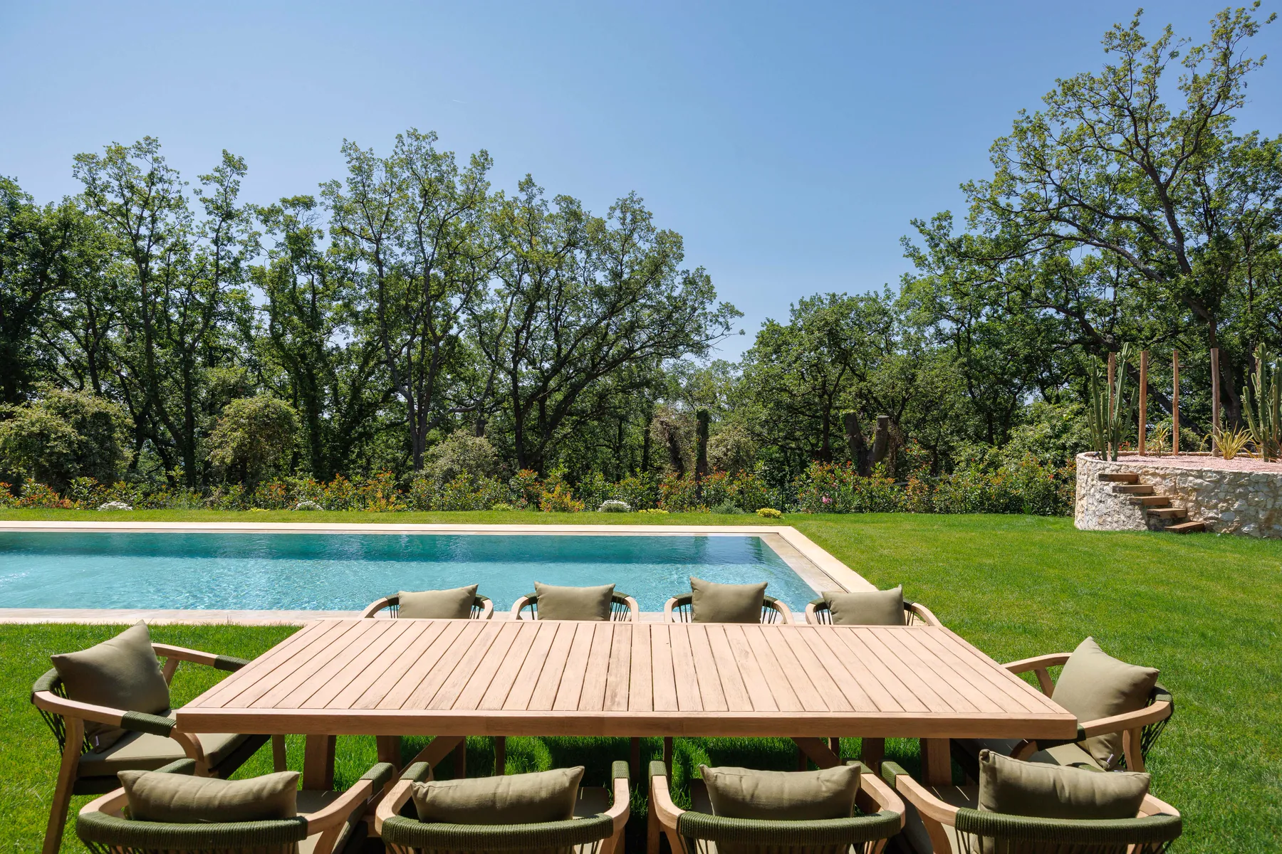 Villa A&G : la table d'été en teck au bord du bassin, sous les chênes