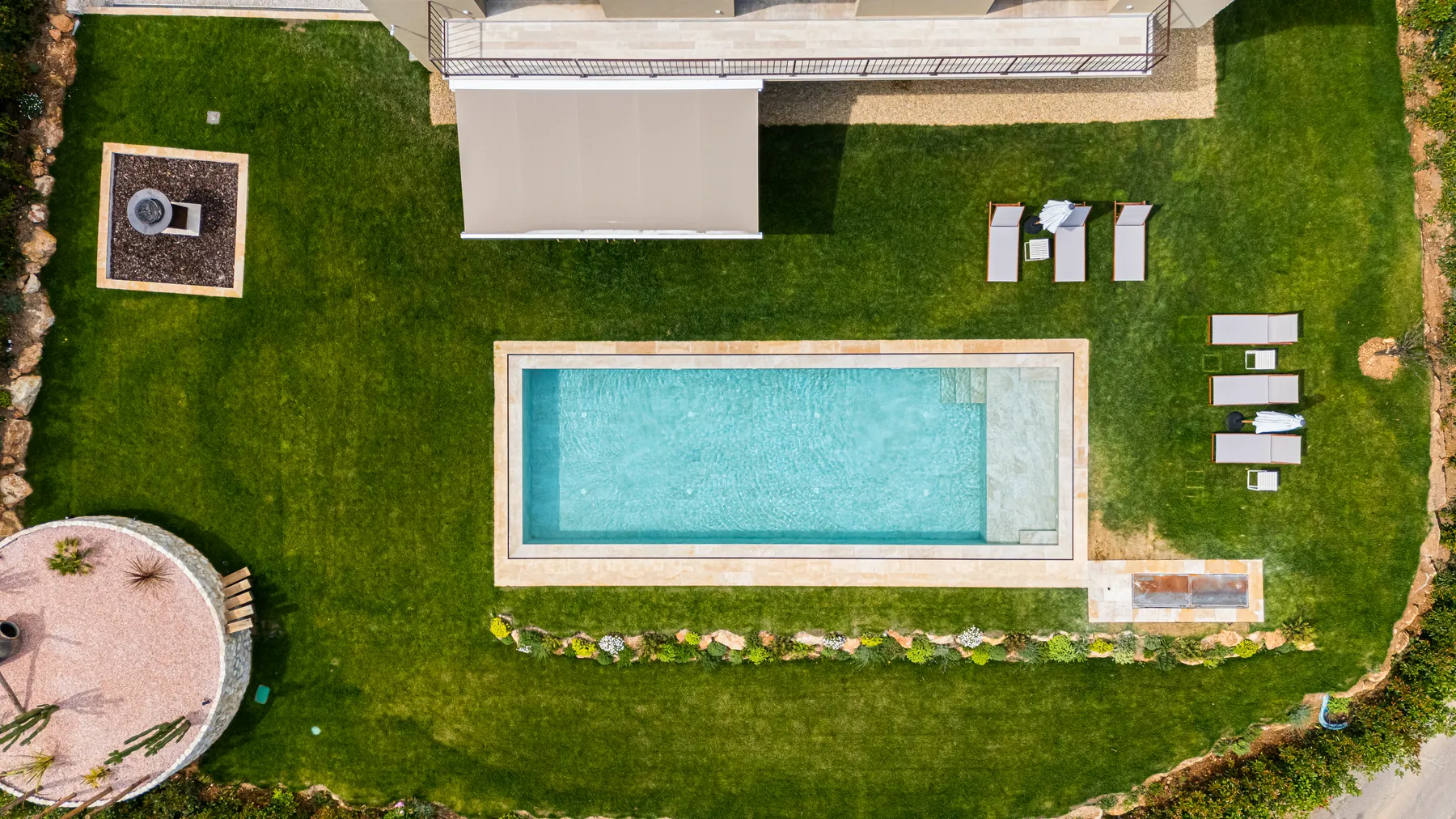 Villa A&G vue du ciel : le bassin rectangulaire, la pelouse, le patio de gravier et les transats