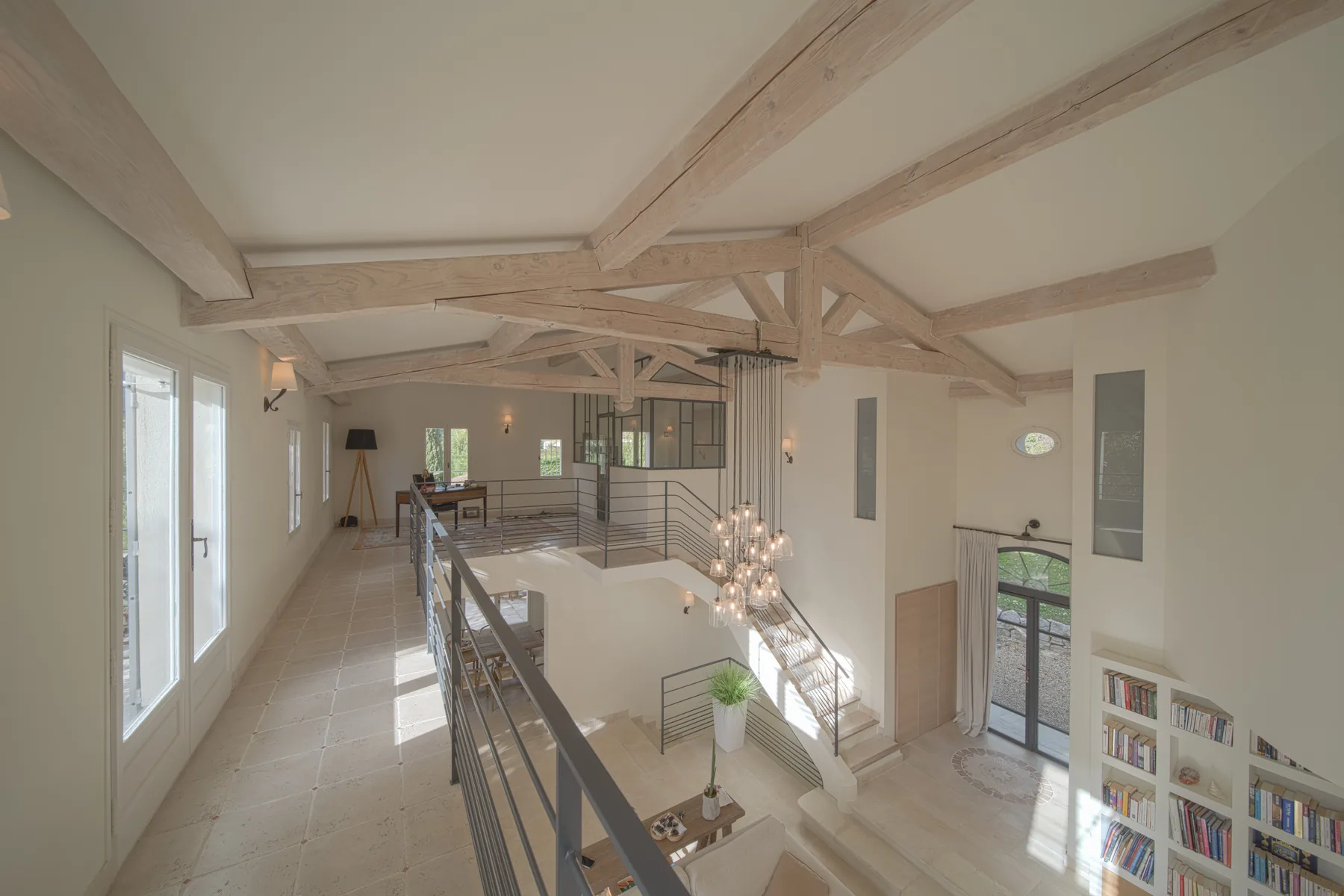 Mezzanine sous les poutres apparentes, garde-corps en métal et escalier ouvert sur le séjour en double hauteur