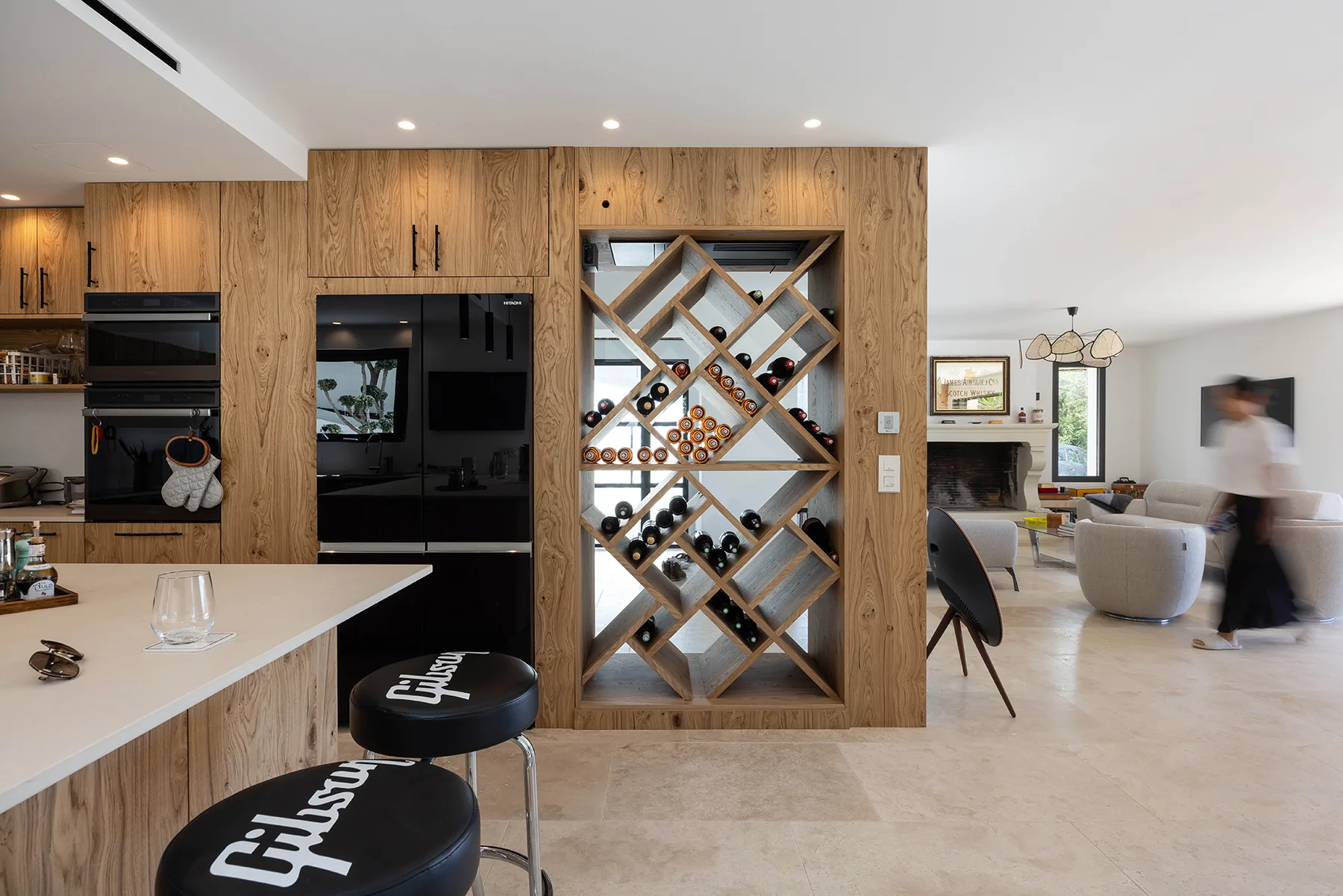 Villa Mélodie : cuisine en chêne, casier à bouteilles sur mesure et perspective sur le salon